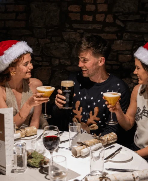 Festive family enjoying drinks in a cosy, warmly lit restaurant setting.