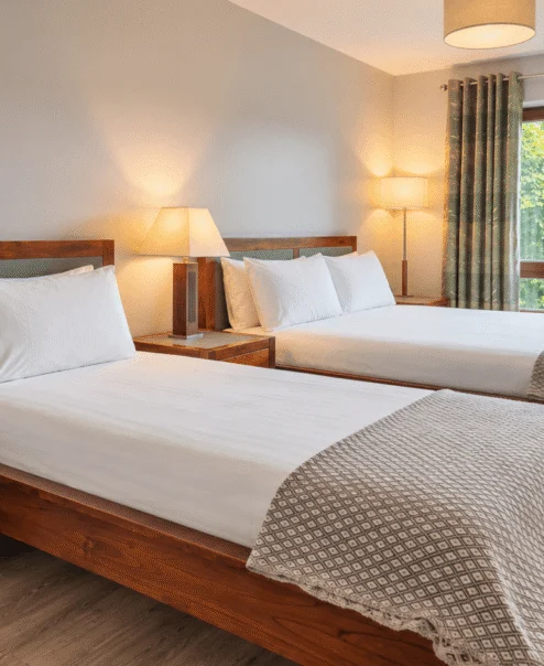 Cosy twin room with warm lighting and garden view at a resort.