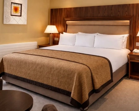Spacious hotel bedroom with king bed, warm wood headboard, bedside lamps and cosy linens for family stays
