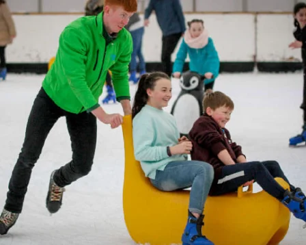 A happy family enjoys ice skating together at a vibrant indoor rink.